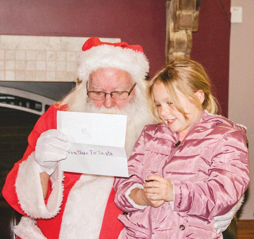 Blaire Hinton shares her letter with Santa Claus in front of the fireplace at the Pour House in Friend on Dec. 14. Mr. and Mrs. Claus had a goodie for every child that came to see them this year.