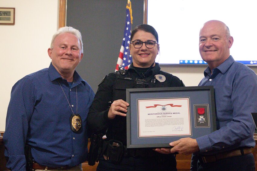 Officer Dawn Jonas is presented the service medal by Chief Gary Young (left) and Mayor Dave Bauer (right) at the March 5 City Council meeting for her work with the Operation Under the Tree Program in Crete.