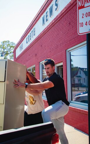 Doane University fullback Eric Halliburton and Ben Berreckman, owner of Ben's Hauling, load archive files from The Crete News to be moved to the Bene Museum on Oct. 8 during building renovations to the office space.