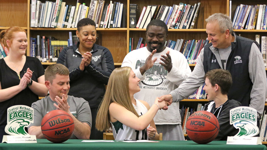 Coach Mike Davis congratulates Abbey Conrow after signing her letter of intent on Thursday. Pictured in the front row are: Jamie, Abbey, and Angie Conrow. In the back row are coaches Valerie Foland, Shavonda Price, Remy Lory and Mike Davis.