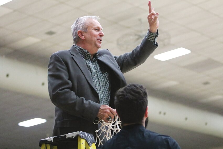 Coach Mike Davis signals “three” to his team, signifying three wins to go to claim a national title, moments after cutting down the net following Central’s NAIA National Championship Second Round win on March 8, 2023.