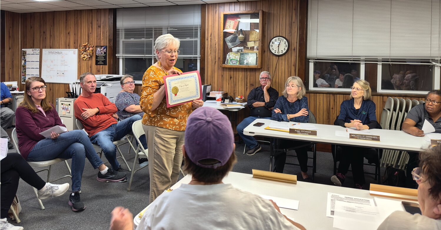 Pam Huttsell displays the 20-year certificate to the Fayette city council.
