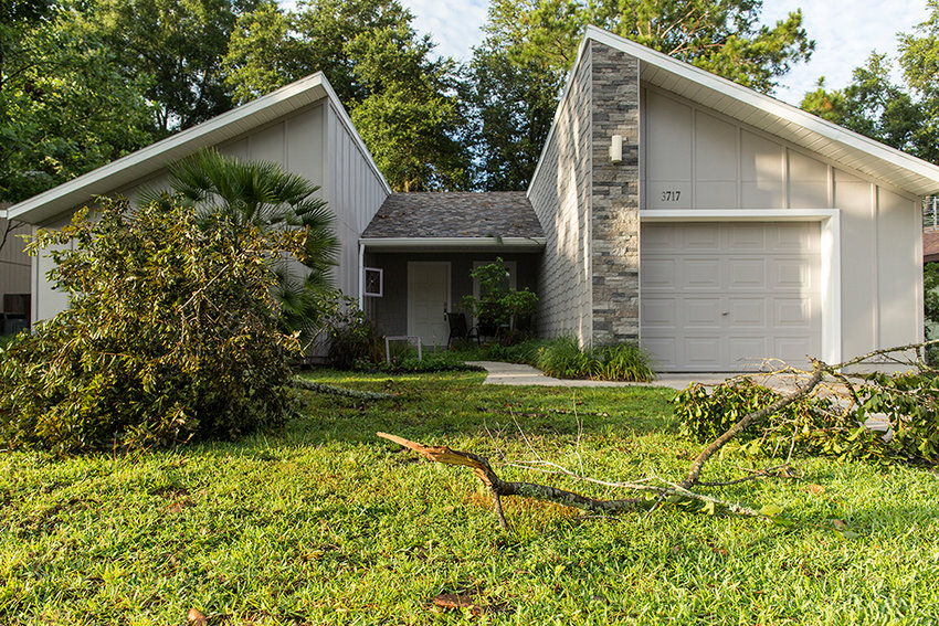 Downed tree limbs and natural yard debris in front of a home after a severe thunderstorm.