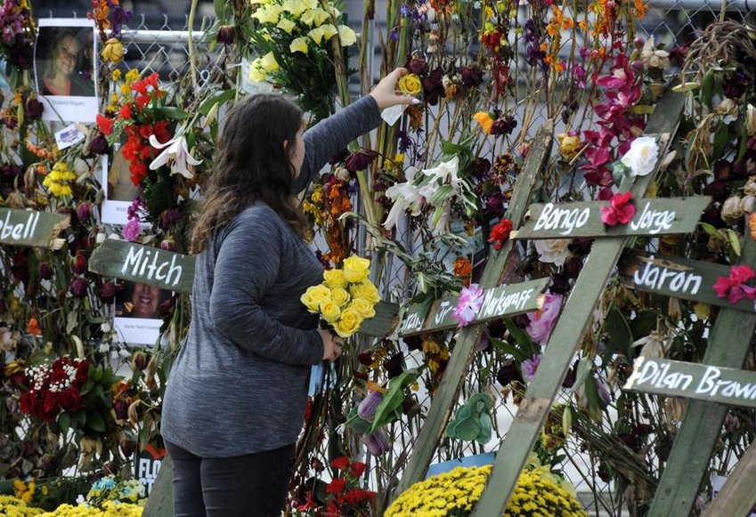 Holly Harmon places a rose into a memorial for victims of Hurricane Ian in Fort Myers, Fla., on Monday, Oct. 10, 2022. More than 100 died during the hurricane, with the greatest number in Lee County. (AP Photo/Jay Reeves)