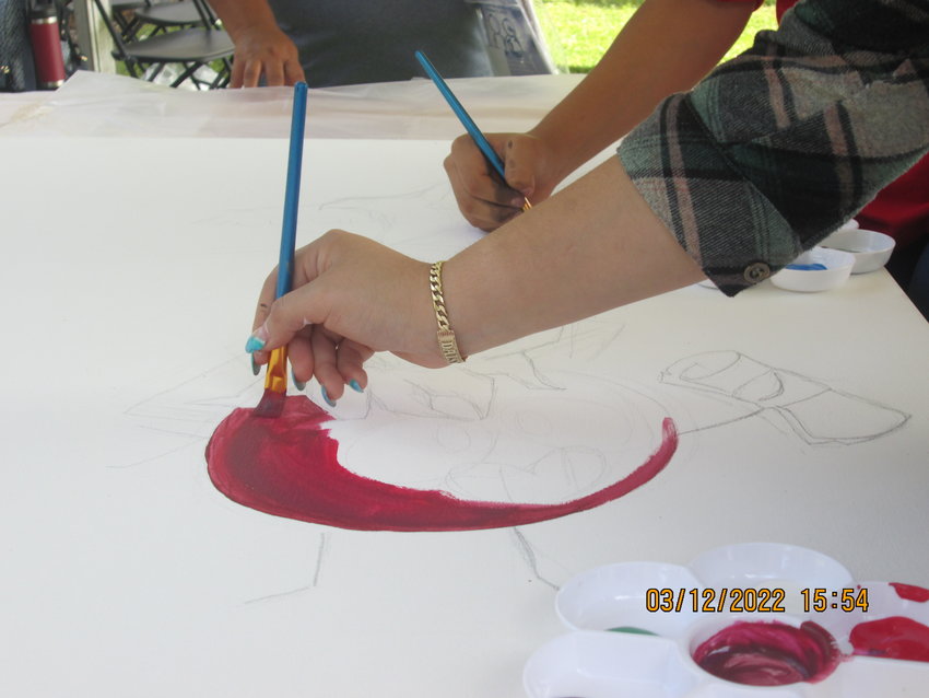 Immokalee Foundation student Daisy H. painting on a large community painting.