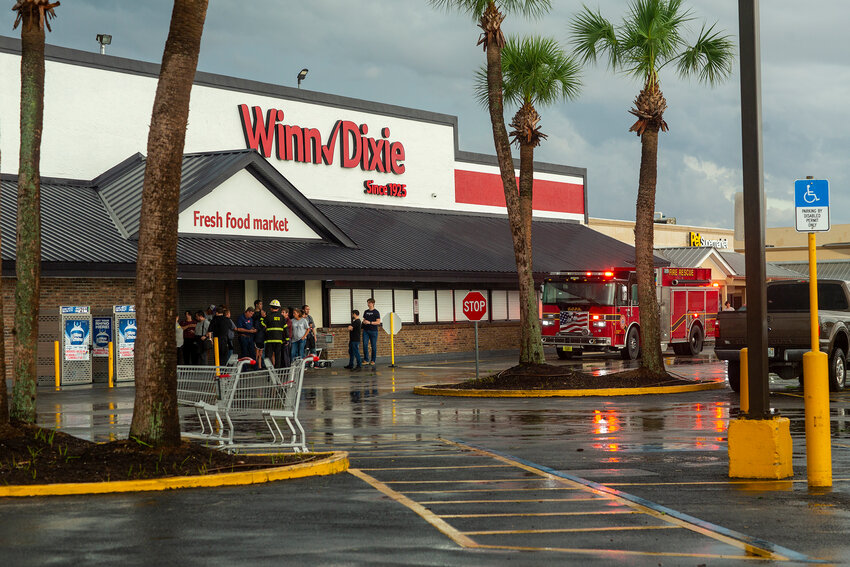 Employees gather at the entrance of Winn-Dixie following a severe storm that damaged the roof.