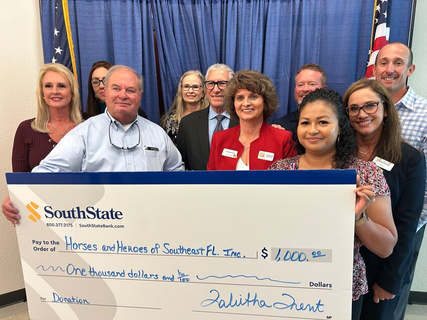SouthState Bank presented Frank Libutti with a $1,000 donation for his non-profit Horses and Heroes. Libutti is pictured center wearing a black suit.
