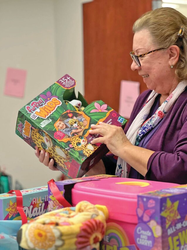 Amparo Gomez, the “Christmas Queen” for CCKids’ Making Christmas Bright program, inspects toys collected from local sponsors. (Photo courtesy CCKids)