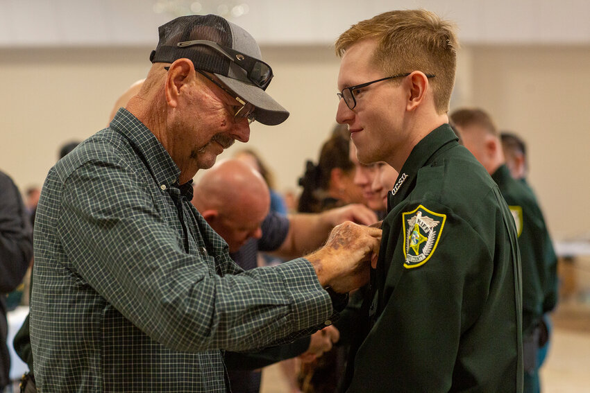 Family members helped pin badges to deputies after they were sworn in. [Photo by Richard Marion]