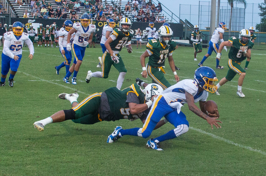 Pope is dragged down by Julian Ramos after scrambling out of the pocket. [Photo by Richard Marion/Lake Okeechobee News]