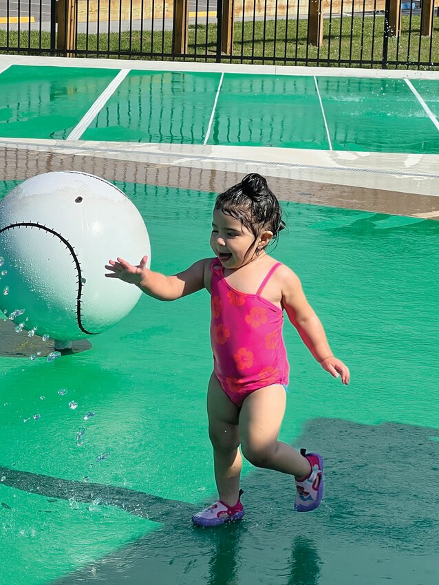 OKEECHOBEE -- Two-year-old Juliana enjoys playing at the splash pad in the Darrell Enfinger Sports Complex in Okeechobee. The splash pad is open during regular park hours. Those using the splash pad can turn on the water by pushing a button. The automatic timer turns the water off. [Photo by Katrina Elsken/Lake Okeechobee News]