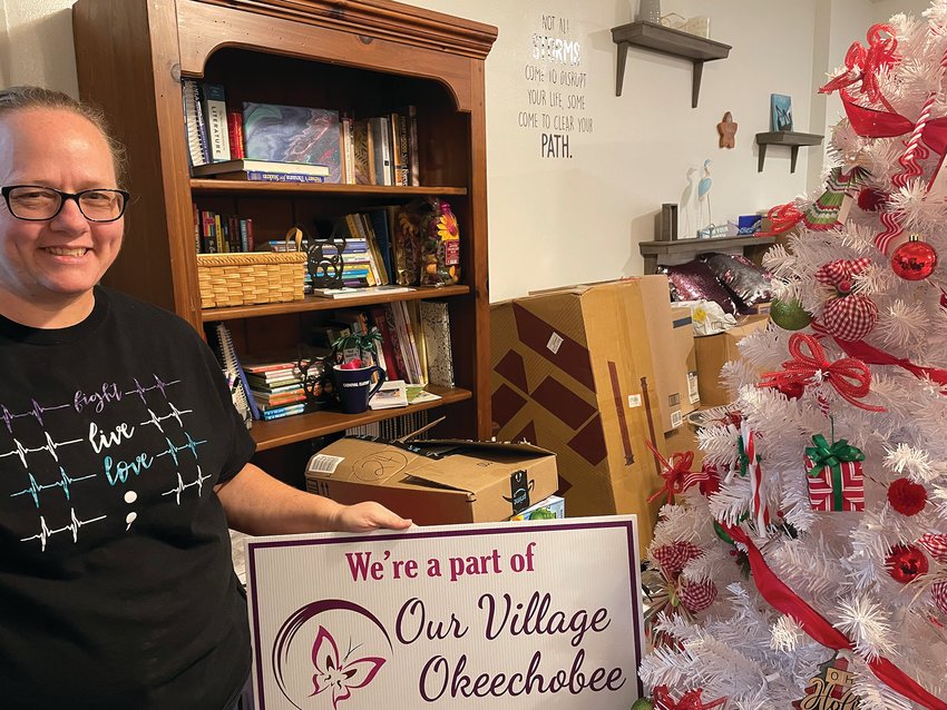 Leah Suarez displays one of the fundraising signs surrounded by boxes of medical equipment and Christmas donations.