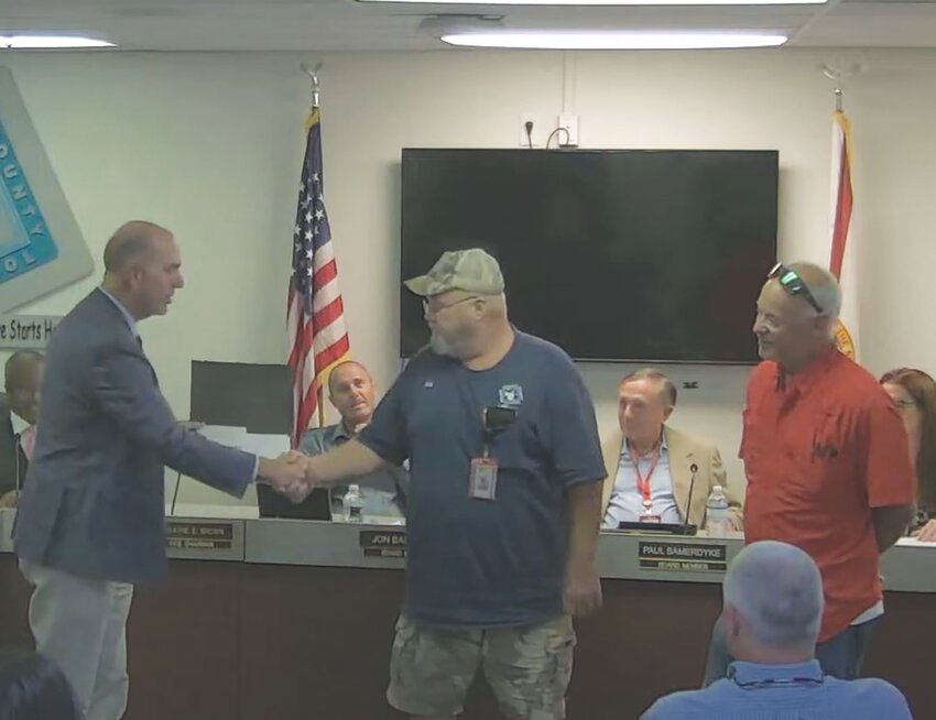 Hendry County Supervisor of Schools Michael Swindle (left) thanks Robert Charles Lord, Jr. for his 10 years of service to the district as Maintenance II for LaBelle Maintenance, during the May 16 school board meeting. Lord is retiring in June. District Facilities, Maintenance and Transportation Director Tony Busin (right) spoke of his dedication to his work, saying he will be missed.
