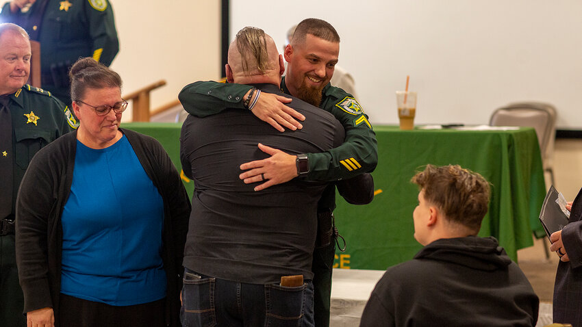 Family members hug Cpl. Cauley after presenting him with an award for saving their relative's life. [Photo by Richard Marion]