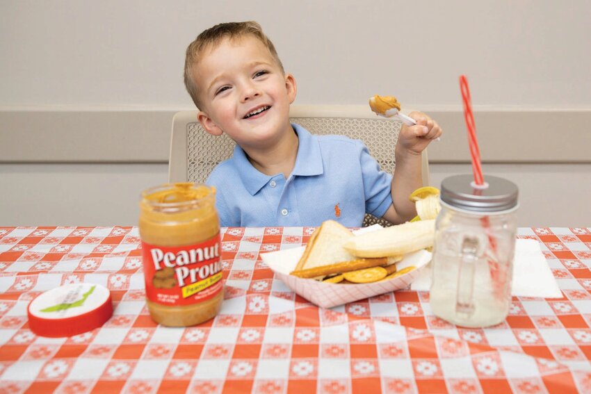 A boy smiles as he prepares to enjoy a scoop of peanut butter.