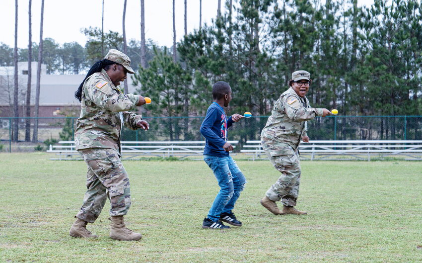 Sgt. 1st Class Ebony Houck, an account manager with U.S. Army Central, and Capt. Leslie Amaya, a G1 strength manager, play a game with a Cherryvale Elementary School student.