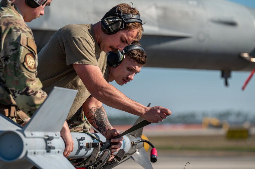 U.S. Air Force Staff Sgt. Nicholas Alford, 77th Fighter Generation Squadron weapons load crew member, center, straps down a missile post-flight during the program March 12.