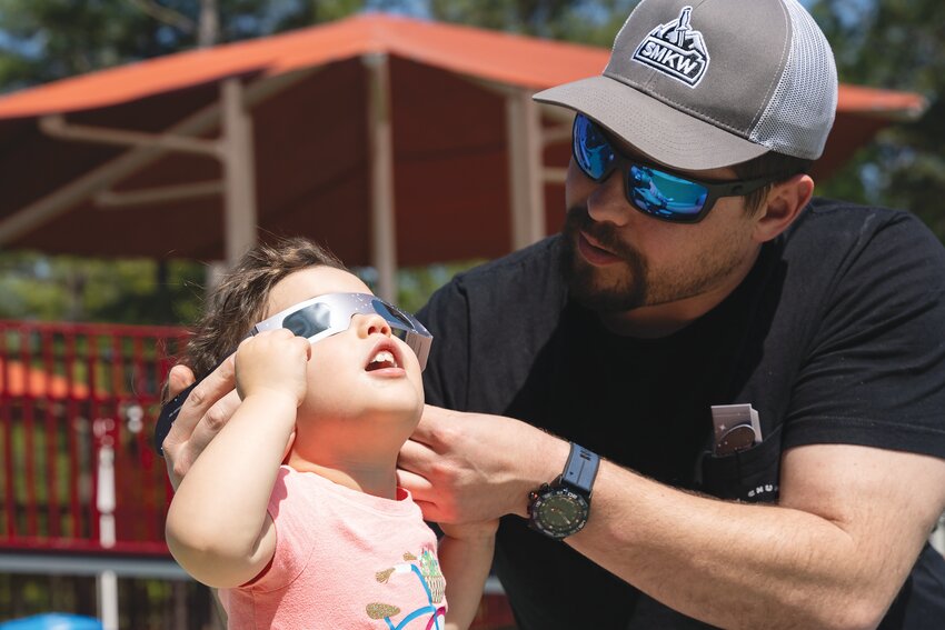 Spencer Pearson helps his daughter, Jemma, view the 2024 solar eclipse from Patriot Park on Monday, April 8.