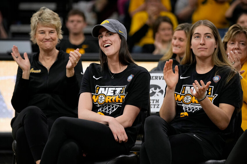 Iowa guard Caitlin Clark, center, sits with coach Lisa Bluder, left, and guard Kate Martin, right, as she finds out her number will be retired, during an Iowa women's basketball team celebration Wednesday, April 10, 2024, in Iowa City, Iowa.
