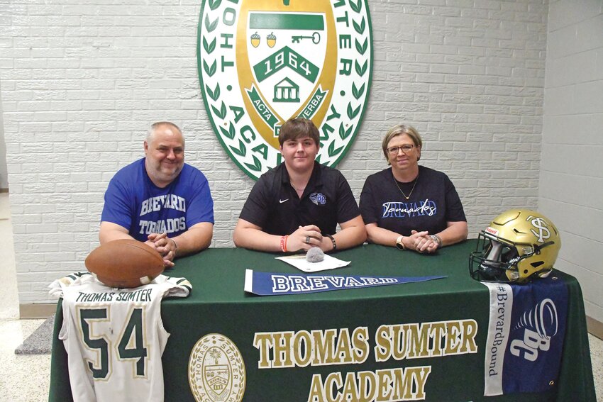 Thomas Sumter's Holden Trimnal, center, is flanked by his parents as he signs to continue his football career at Brevard on Wednesday.