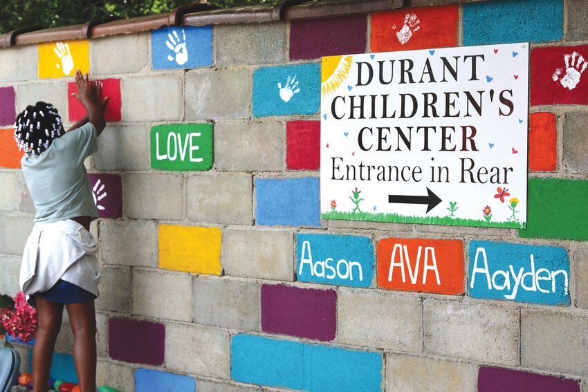 Attendees leave their mark on the garden wall in honor of Sumter's Angels at Durant Children's Center on April 27 during the Heart2Heart Community Fair.    LEFT: Photographs of Sumter's Angels, Ava Holliday, Aason Holliday-Slacks and Aayden Holliday-Slacks, who died in 2023, are displayed during the event.