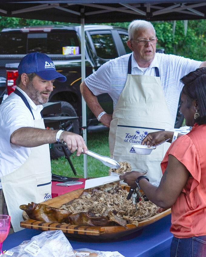 Will Buyck, left, and Lannes Prothro serve barbecue at the May 16 Taste of Clarendon that was held at John C. Land III Landing on Greenall Road in Summerton. The duo was chosen by the attendees as having the best dish at the event.