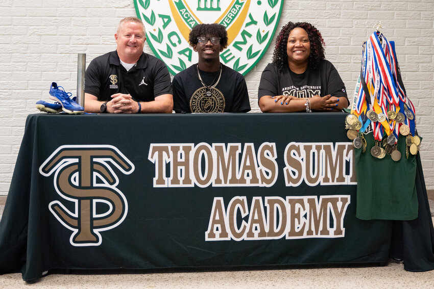 Thomas Sumter's William Wright, center, is flanked by his mother and Thomas Sumter head coach Rob Coursey, left, after signing to run track at Anderson on Tuesday.