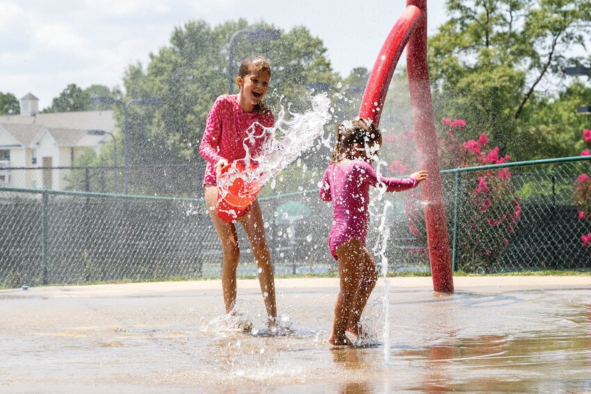Henley, left, and Marsha play in the water at Palmetto Park on Tuesday, July 16. There are several spray parks throughout the county for families to cool off in.