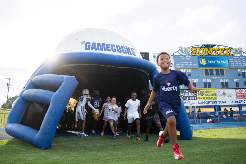 Campers run out of the tunnel during Sumter High's annual youth football camp on Tuesday at Memorial Stadium.