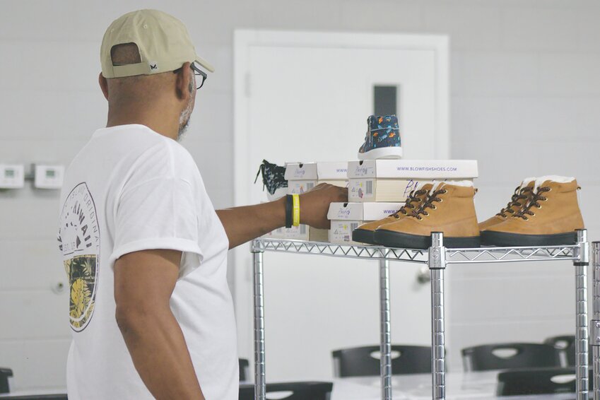 Sarah Tindal's husband picks out a pair of shoes for a young boy to try on at Tindal's annual free shoe giveaway.