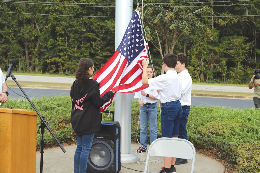 Furman Middle School's Tribe Cadet Program raise the American flag to half-staff on Wednesday morning in front of the school.