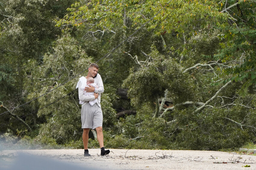 ADAM FLASH / THE SUMTER ITEM    Hurricane Helene passed through Sumter on Thursday, Sept. 26 as crews worked to repair the damage the following morning, Friday, Sept. 27. A Mood Avenue resident walks in the road with his baby as a huge tree fell in the night, blocking the street and causing power outages.