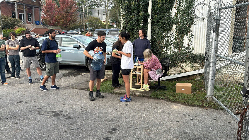 People wait to gather water at Mountain Valley Water in the aftermath of Hurricane Helene in West Asheville, N.C., Monday, Sept. 30.