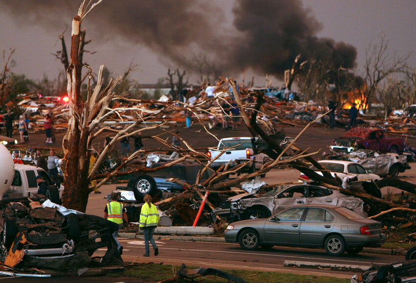 In this May 22, 2011 file photo, emergency personnel walk through a severely damaged neighborhood after a tornado hit Joplin, Mo.