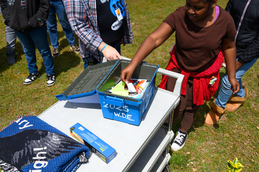 A fifth-grade student places a slip of paper in the Willow Drive Elementary School time capsule on Friday, April 11, 2025. Students buried the time capsule as part of Willow Drive's 75th anniversary celebration. 