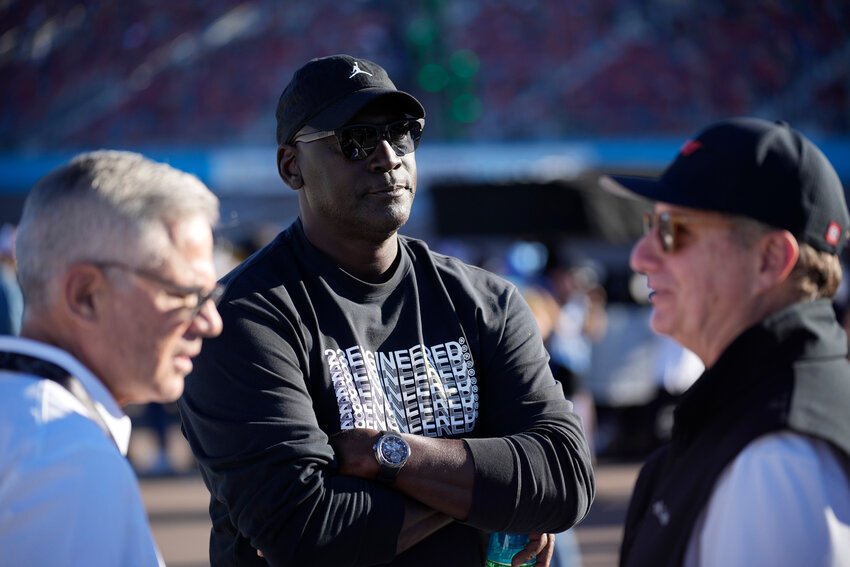 Michael Jordan, center, and Curtis Polk, left, co-owners of 23XI Racing, watch during qualifying beside 23XI Racing President Steve Lauletta, right, for a NASCAR Cup Series Championship auto race, Nov. 9, 2024, in Avondale, Ariz.
