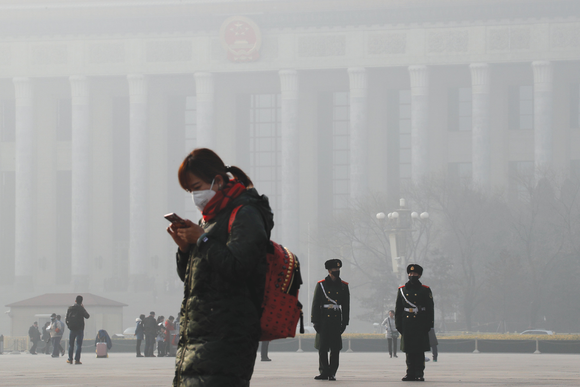 A woman walks past Chinese paramilitary policemen wearing a protection mask on Tiananmen Square in Beijing as the capital of China is blanketed by heavy smog in 2017. China has long faced some of the worst air pollution in the world, blamed on its reliance of coal for energy and factory production, as well as a surplus of older, less-efficient cars on its roads. Inadequate controls on industry and lax enforcement of standards have worsened the pollution problem.