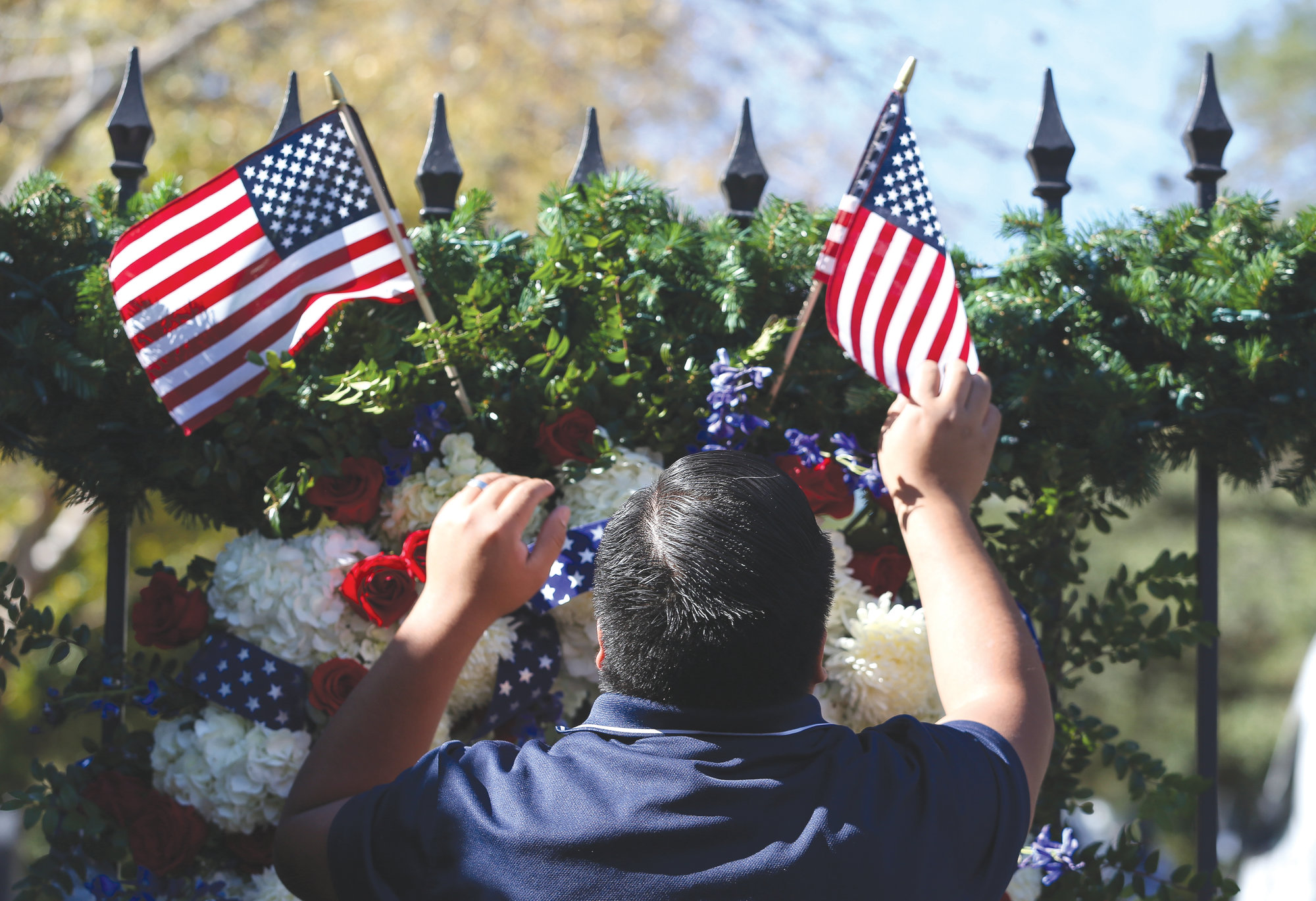 THE ASSOCIATED PRESSErick Herrera makes sure the two small American flags are placed correctly on the presidential wreath on the gate outside of former President George H.W. Bush's residence on Dec. 1 in Houston.