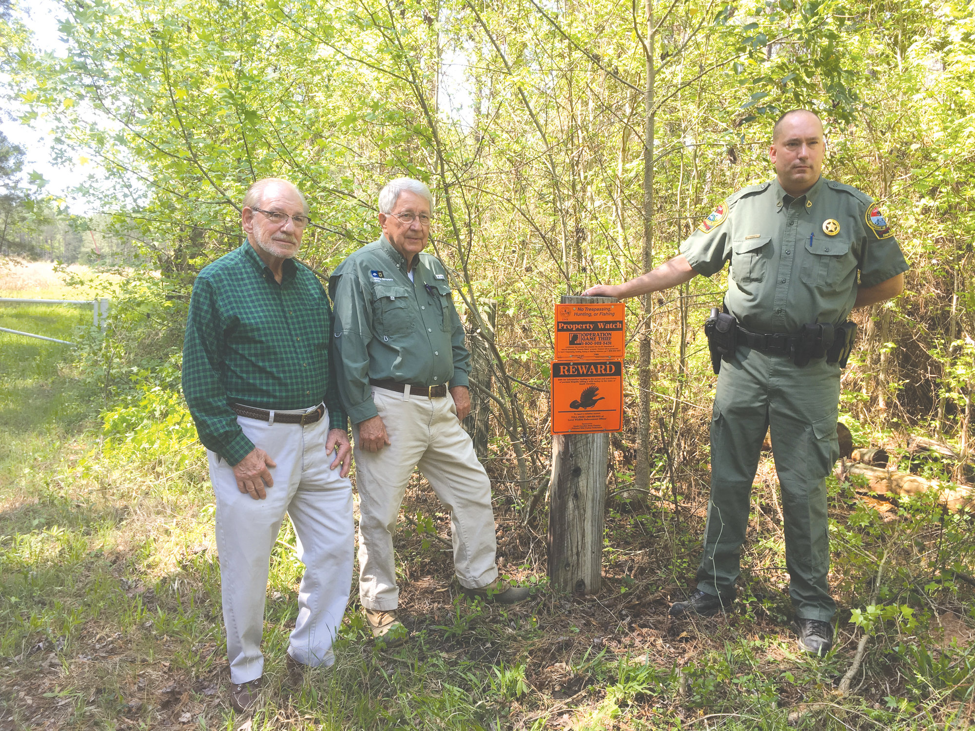 Landowners Marvin Davant, Hugh Ryan and SCDNR Officer Ed Laney are seen at the posted entrance to a rural property.