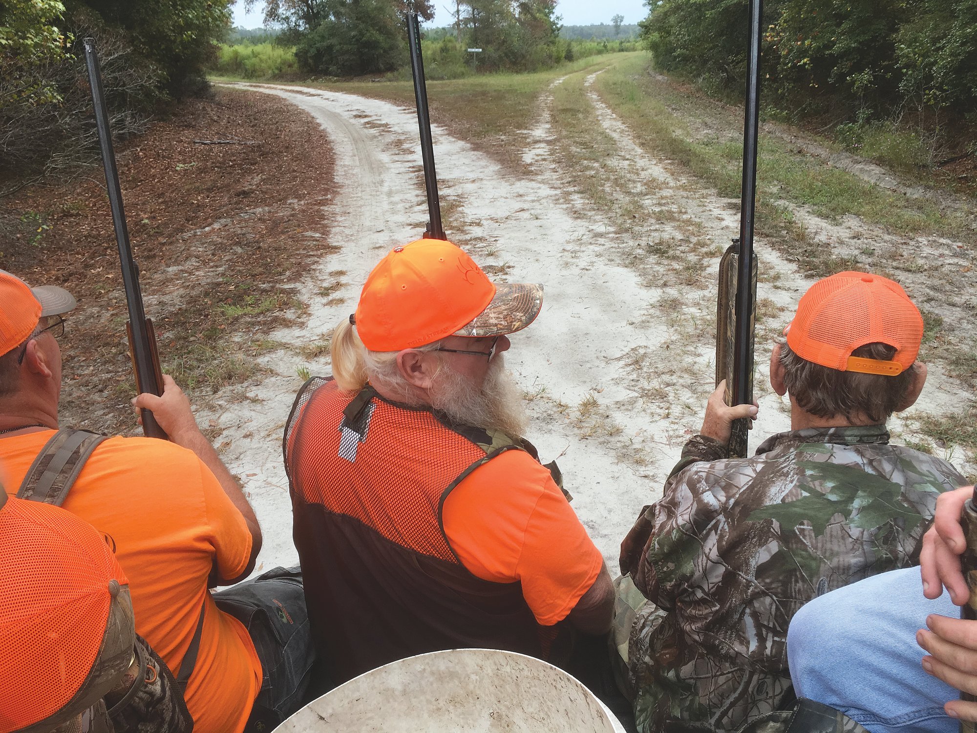 Deer hunters ride on the back of a truck, heading out to their stands.