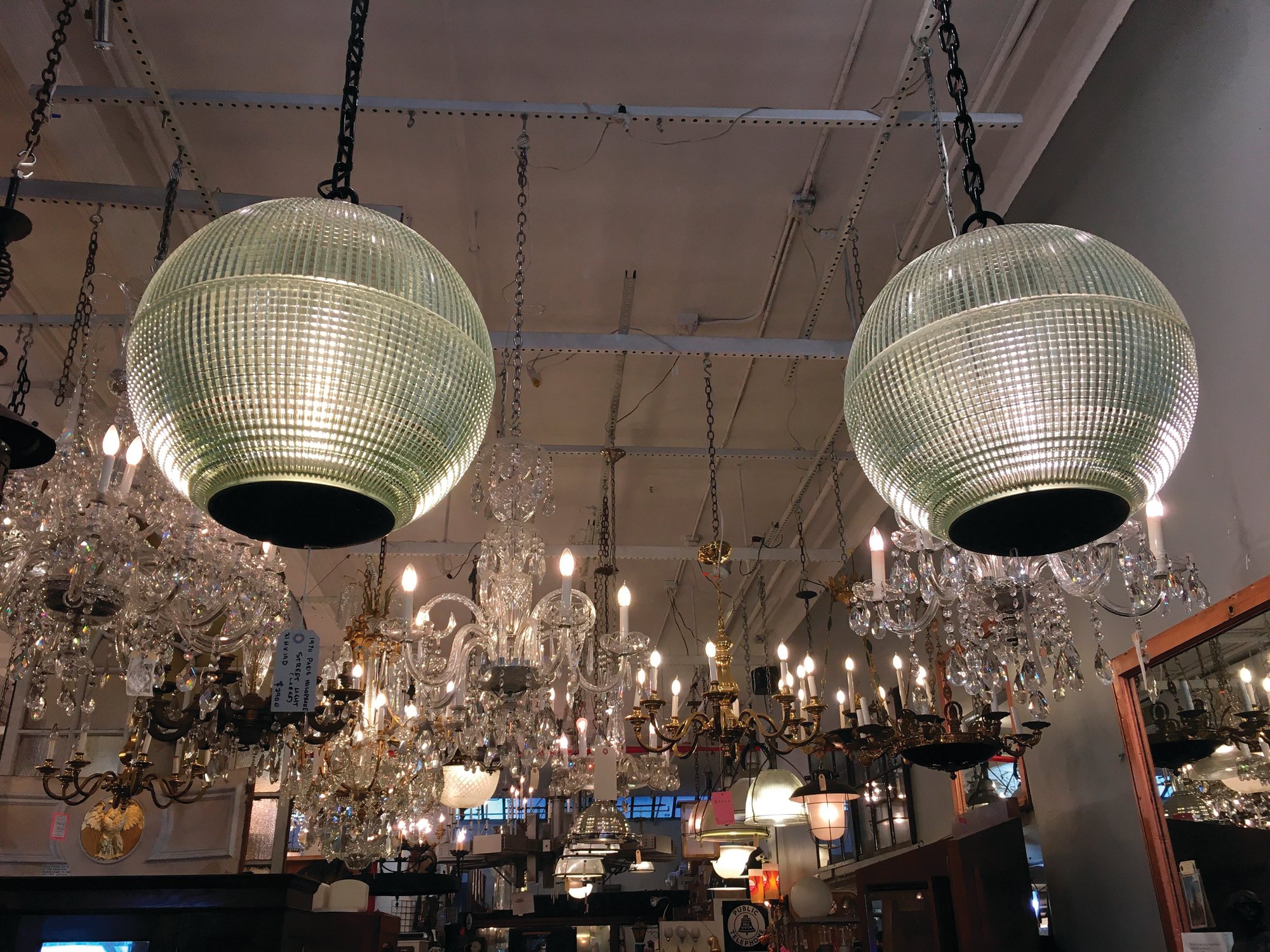 Seen are two light fixtures reconfigured as pendant lamps from Paris street lamps, available for sale at Olde Good Things salvage store in New York.