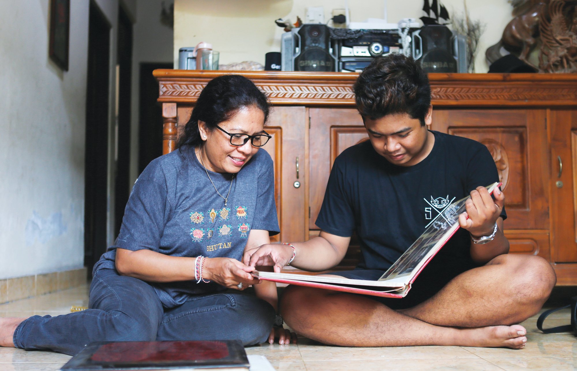 Ni Luh Erniati and her son, Made, go through family photo albums which show her late husband and his late father, Gede Badrawan, in Bali, Indonesia.  Gede was one of 202 people killed in the 2002 Bali bombings. After his death, the sight of Erniati's tears made Made cry, so she shut herself in the bathroom to weep alone. She spent years telling him that his father was simply away for work. He was 9 before she told him the truth.