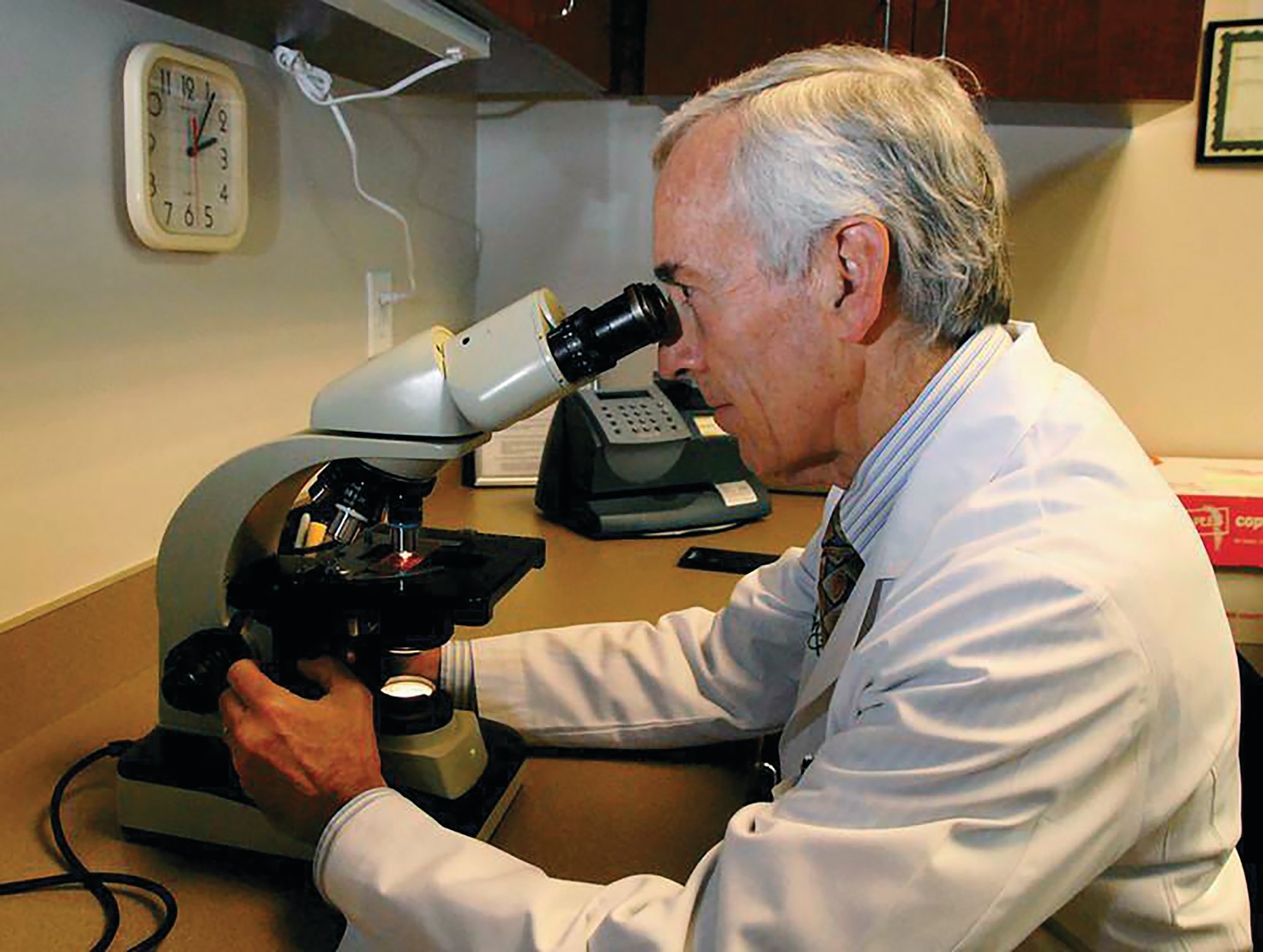Robin B. Panethere / Atlanta Allergy & Asthma via AP   Dr. Stanley Fineman examines pollen through a microscope at Atlanta Allergy & Asthma Center in Atlanta.