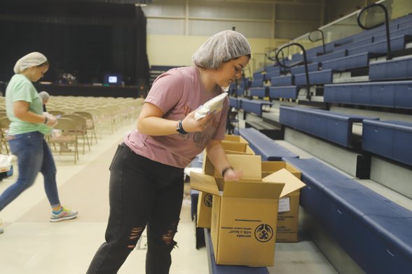 Abby Farmer sets prepared meals in a box on Saturday at "One Weekend."