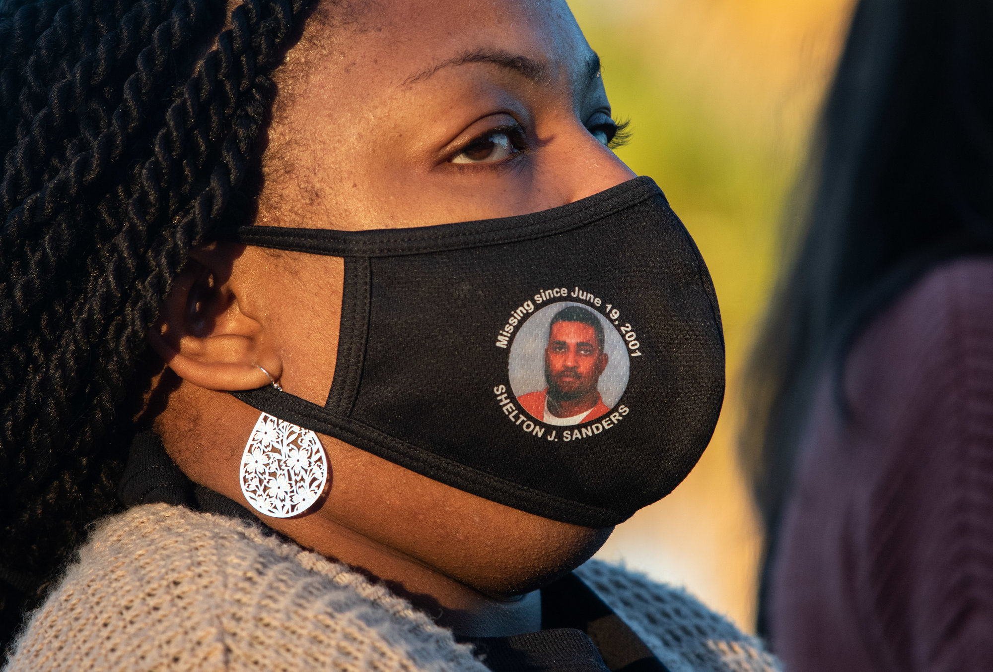 Wilveria Sanders wears a mask dedicated to Shelton, Sanders who went missing over 20 years ago on June 19, 2001.