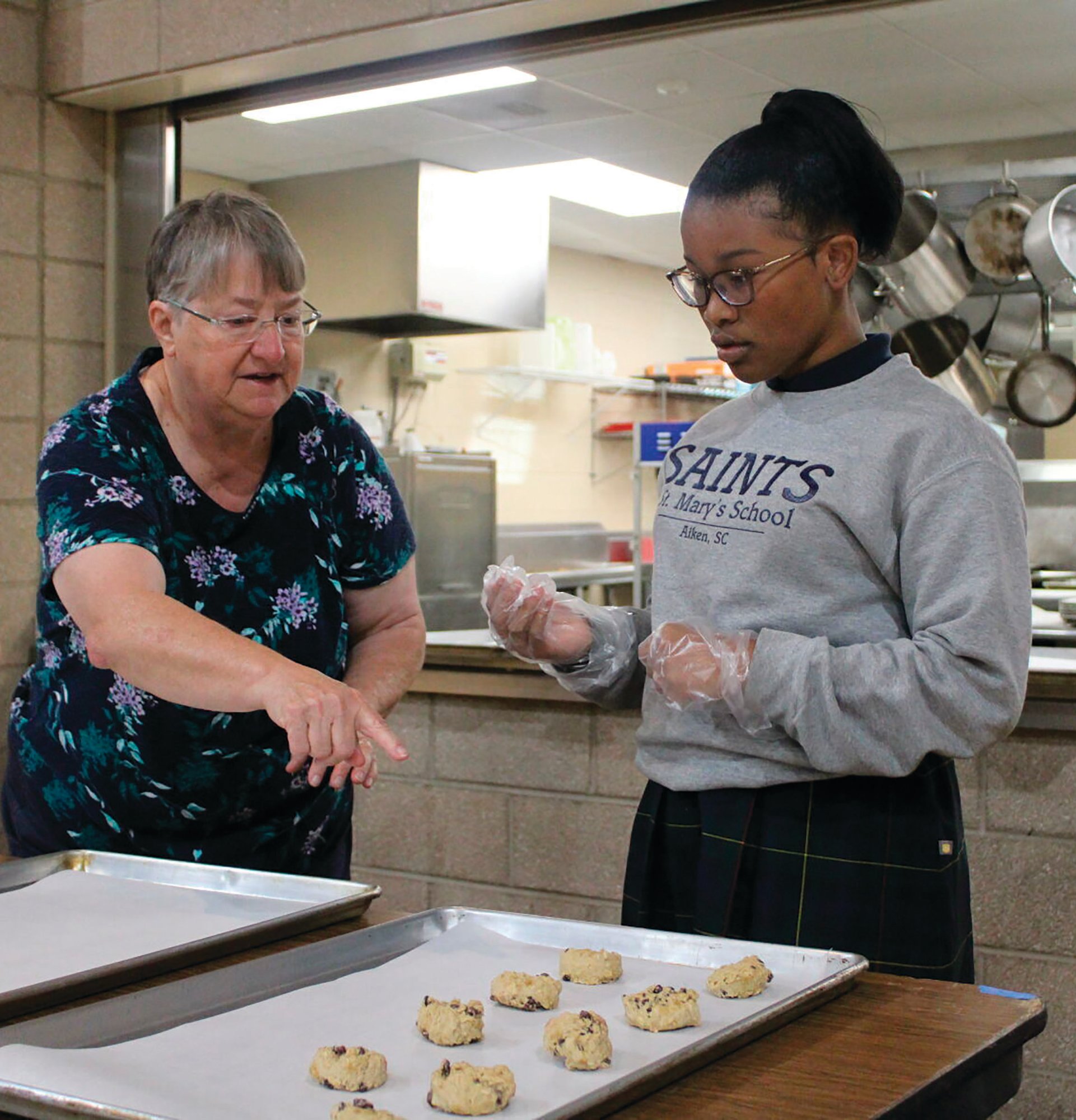 St. Mary Help of Christians youth director Joan LaBone helps sixth-grader Jordon Robinson bake cookies on Oct. 27, 2022 in Aiken, S.C. As a way to teach children the importance of giving back, students at St. Mary Help of Christians Catholic School recently baked cookies for men who are prisoners at Broad River Correctional Institution located outside of Columbia.
