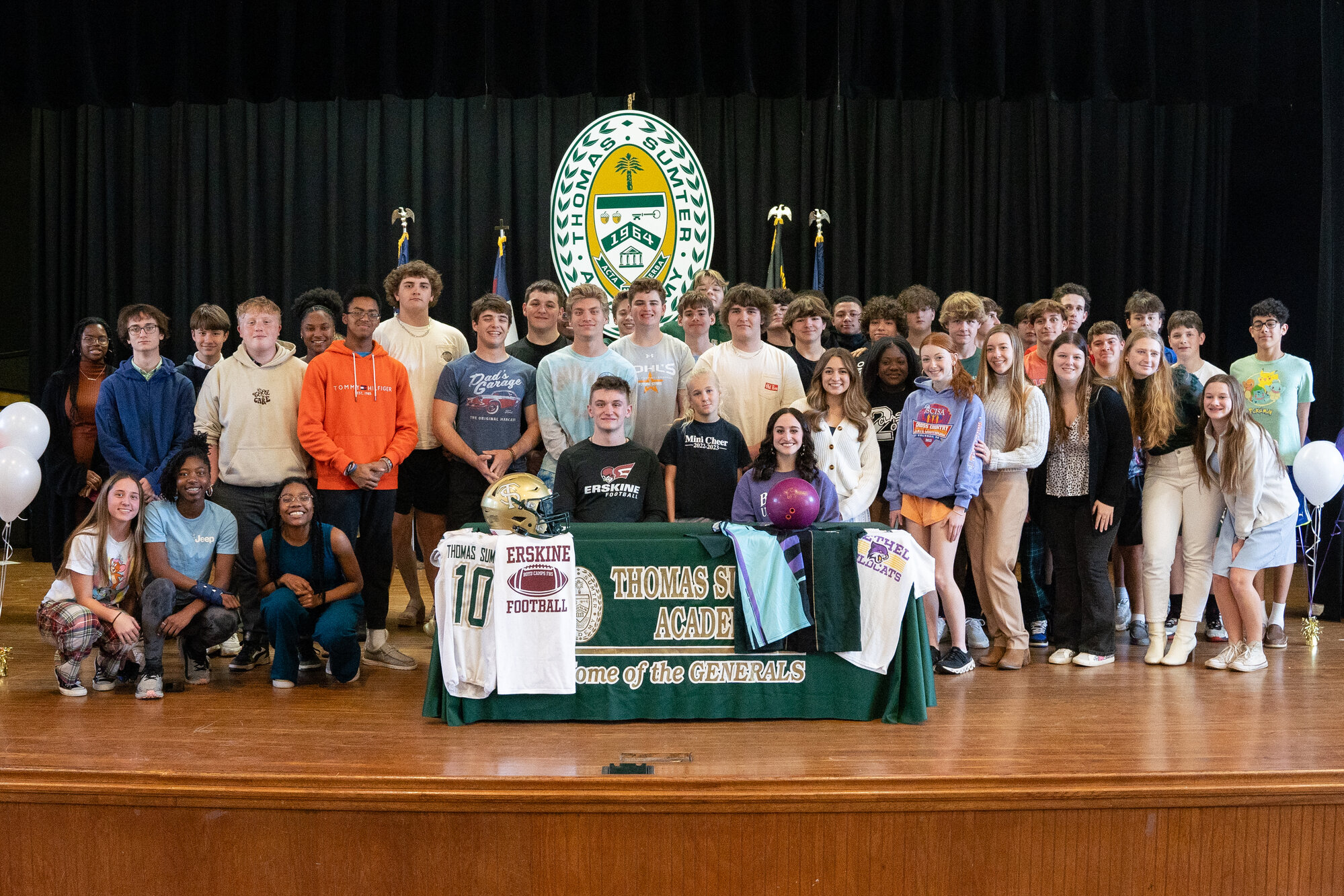 Thomas Sumter's Noah Steele-Allen, seated left, and Ava Teeters, seated right, are surrounded by friends after signing to continue their athletic careers in college.