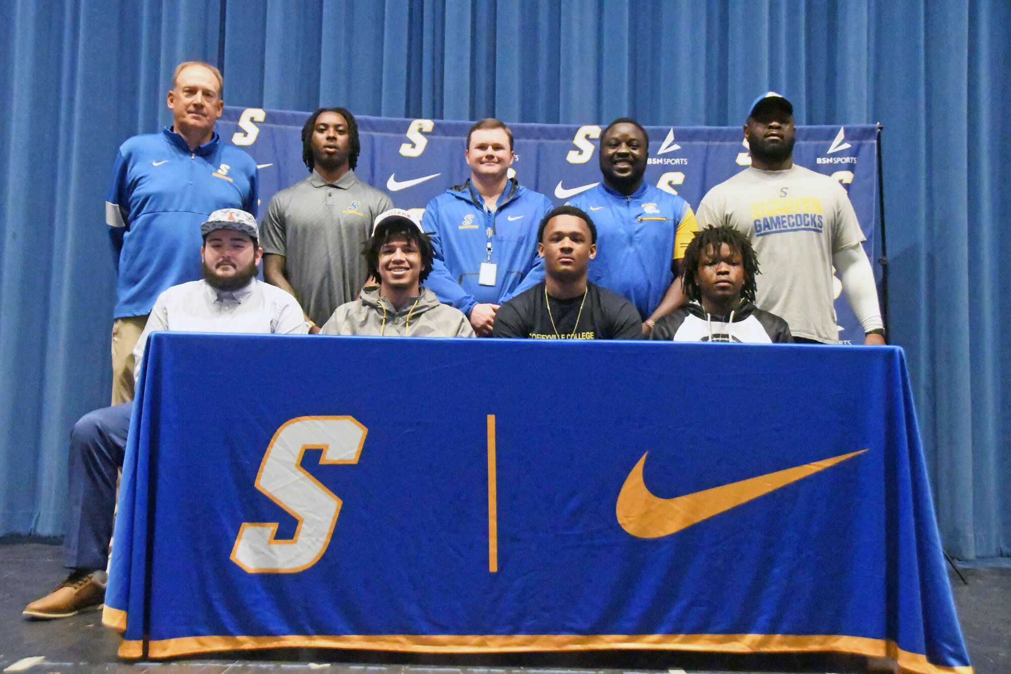 Seated, from left, Sumter High's Ashton Barr, Jamie Tedder Jr., AJ Bracey and Jauron Bennett are joined by Sumter High coaching staff after signing to continue their football careers.